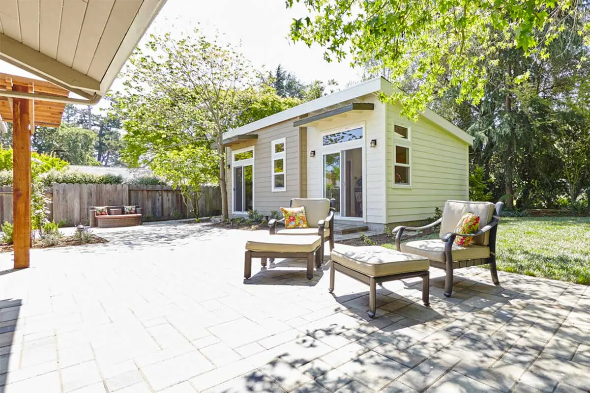 A ADU house in a garden with two chairs and one table