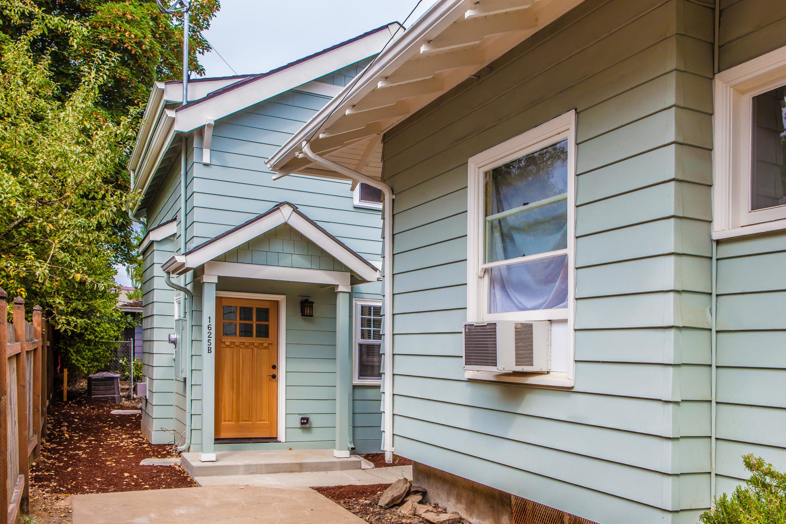 A sky blue ADU house with windows and wood door